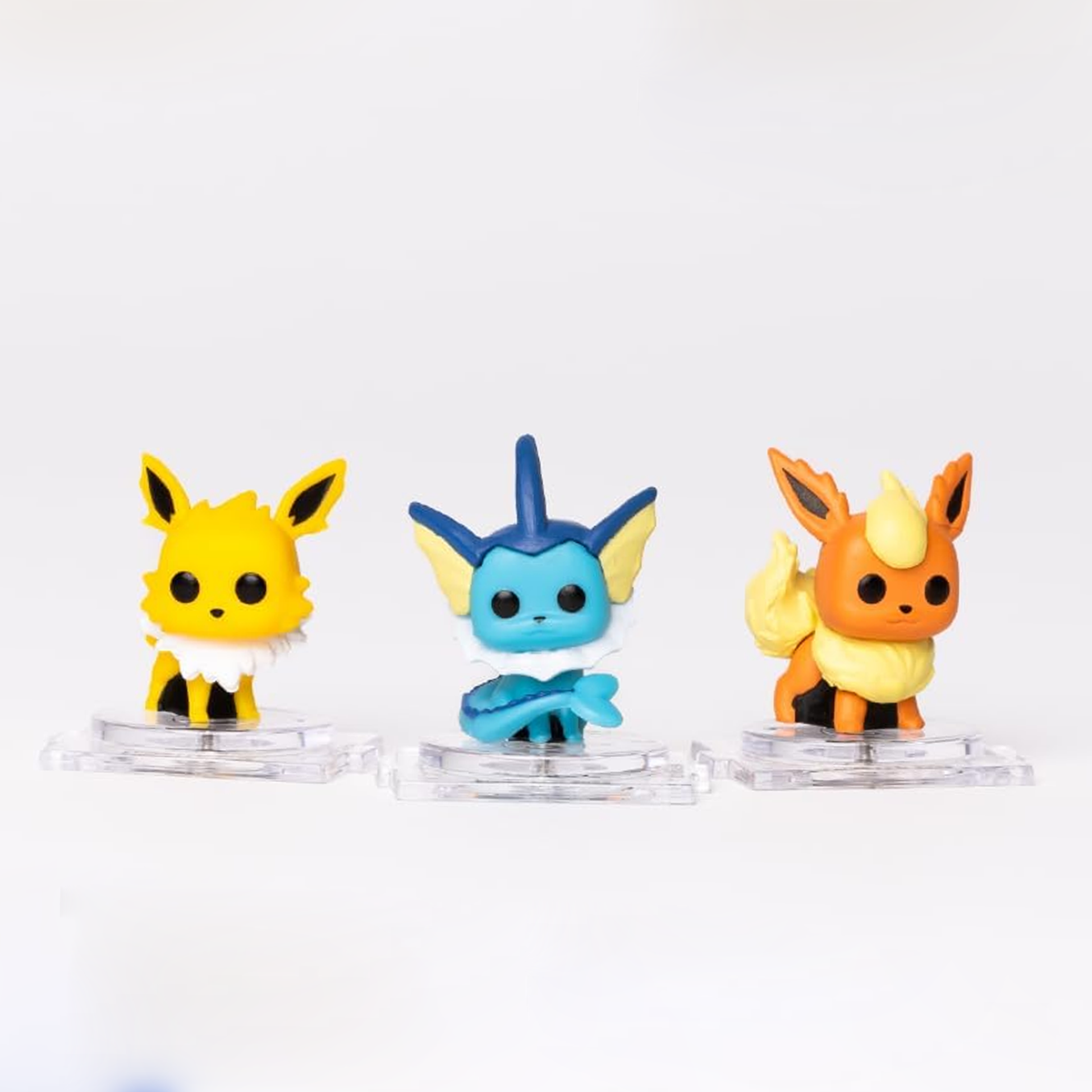 Three colorful figurines on clear stands against a white background