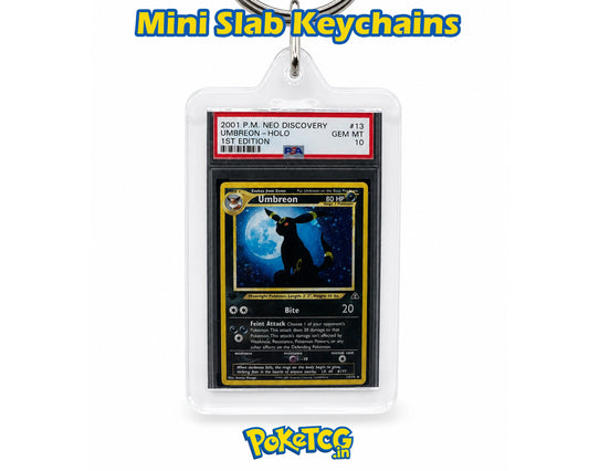 A clear acrylic keychain holder containing a graded holographic Umbreon Pokémon trading card, shown on a white background with 'Mini Slab Keychains' text at the top and a 'Pokémon' logo at the bottom.