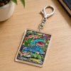 A Pokémon TCG acrylic keychain featuring a colorful Charizard card design, attached to a silver metal lobster clasp, resting on a light wood desk.
