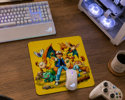 A rectangular gaming mousepad with rounded corners featuring a colorful illustration of a character with Pokémon, placed on a wooden desk alongside a keyboard, mouse, controller, and a cup of coffee.