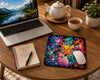 A large rectangular gaming mousepad with a colorful Yu-Gi-Oh! anime character print, shown on a wooden desk with a black gaming mouse resting on it. Surrounding the mousepad are a keyboard, monitor, PC tower with RGB lighting, and headphones.