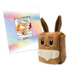 A brown plush toy shaped like a cube with long bunny ears and a cream-colored front panel, shown next to a Pokémon card on a white background with a pastel rainbow pattern.