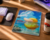A Pokémon trading card featuring Psyduck and Ram displayed on a wooden desk next to a keyboard, mouse, and a Pokéball-themed cup.
