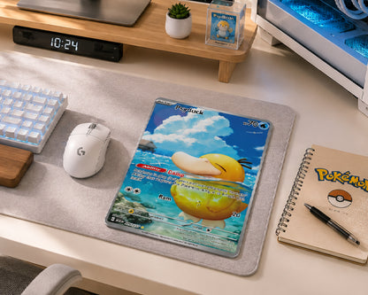 A Pokémon-themed desk mat featuring Charizard card art, styled on a light gray desk mat over a beige desk surface with a keyboard, mouse, notebook, and small plant in a home office setting.