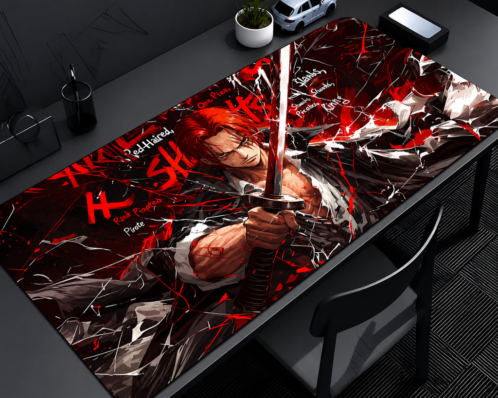 Red-Haired Shanks One Piece extended gaming mouse pad featuring the red-haired swordsman holding a sword against a dramatic red, black, and white background with crimson energy streaks and shattered graphic effects, displayed on a dark gaming desk with a monitor, miniature car, and desktop accessories.