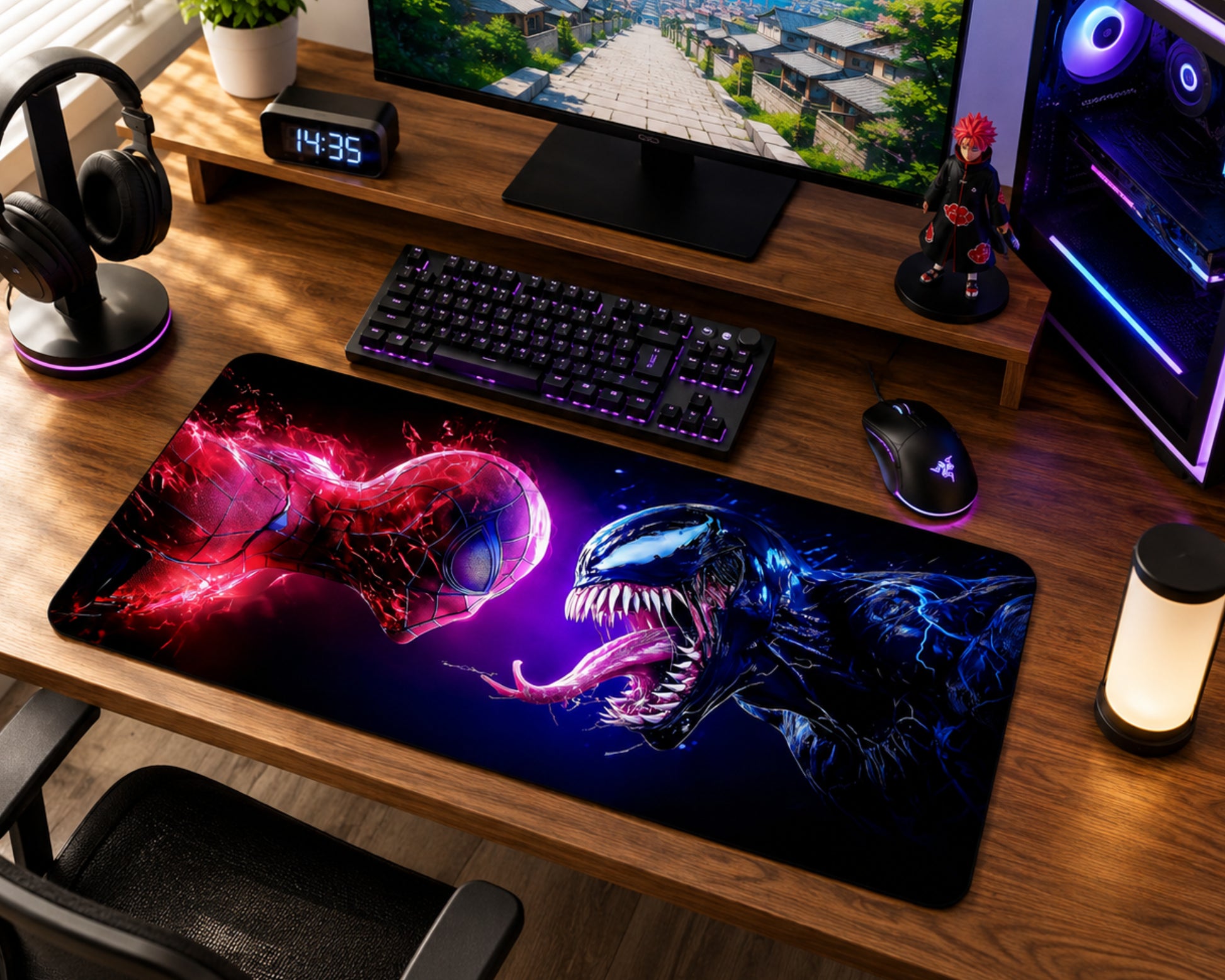 A large gaming desk mat featuring a dramatic Spider-Man and Venom face-off design in vibrant red, purple, and blue, shown on a wooden desk alongside a keyboard, mouse, headphones, and computer setup.