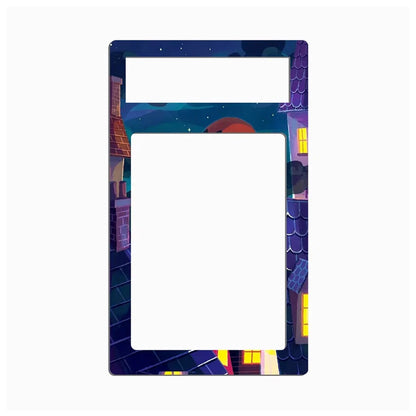 A decorative picture frame with a colorful night village scene border, featuring stylized houses, windows, stars, and a moon around a large blank white center.