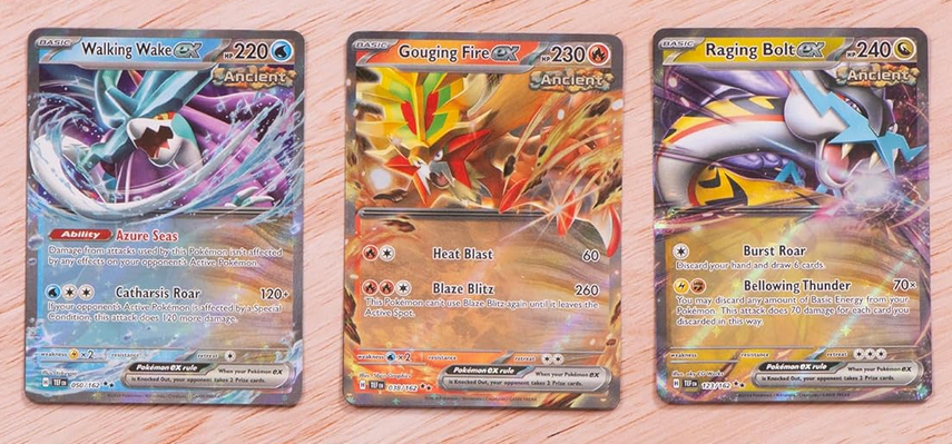 Three trading cards featuring different characters on a wooden surface