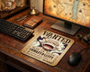 Vintage One Piece Monkey D. Luffy wanted poster anime mouse pad on rustic wooden gaming desk with mechanical keyboard, pirate map monitor wallpaper, and nautical decor aesthetic
