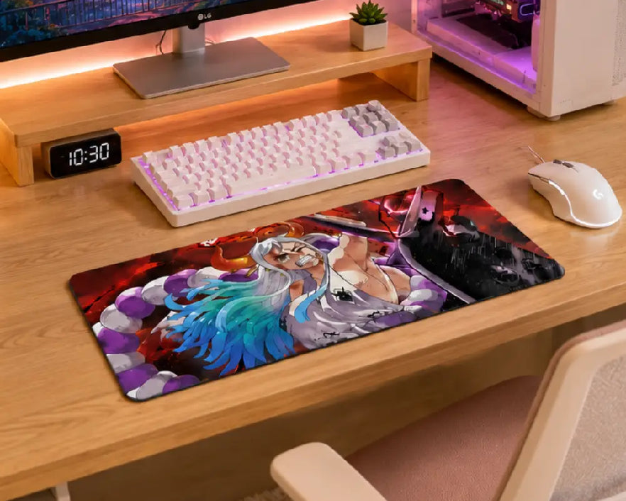 A large rectangular gaming desk mat with a colorful anime-style character print, shown on a light wood desk alongside a white mechanical keyboard, white mouse, and computer tower.