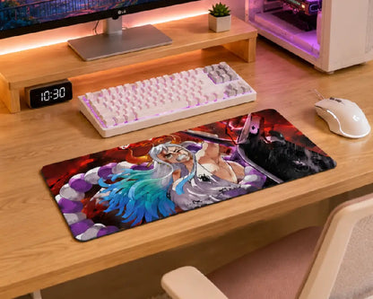 A large rectangular gaming desk mat with a colorful anime-style character print, shown on a light wood desk alongside a white keyboard, mouse, and monitor stand.