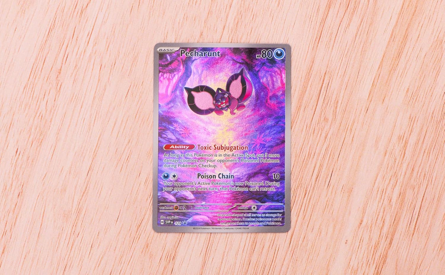 Pokémon trading card featuring a character with butterfly wings on a wooden surface
