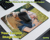A custom-printed rectangular desk mat or mouse pad shown on a white desk, featuring a printed photo of a woman holding a child outdoors. A black computer mouse is placed on top of the mat as a demonstration.