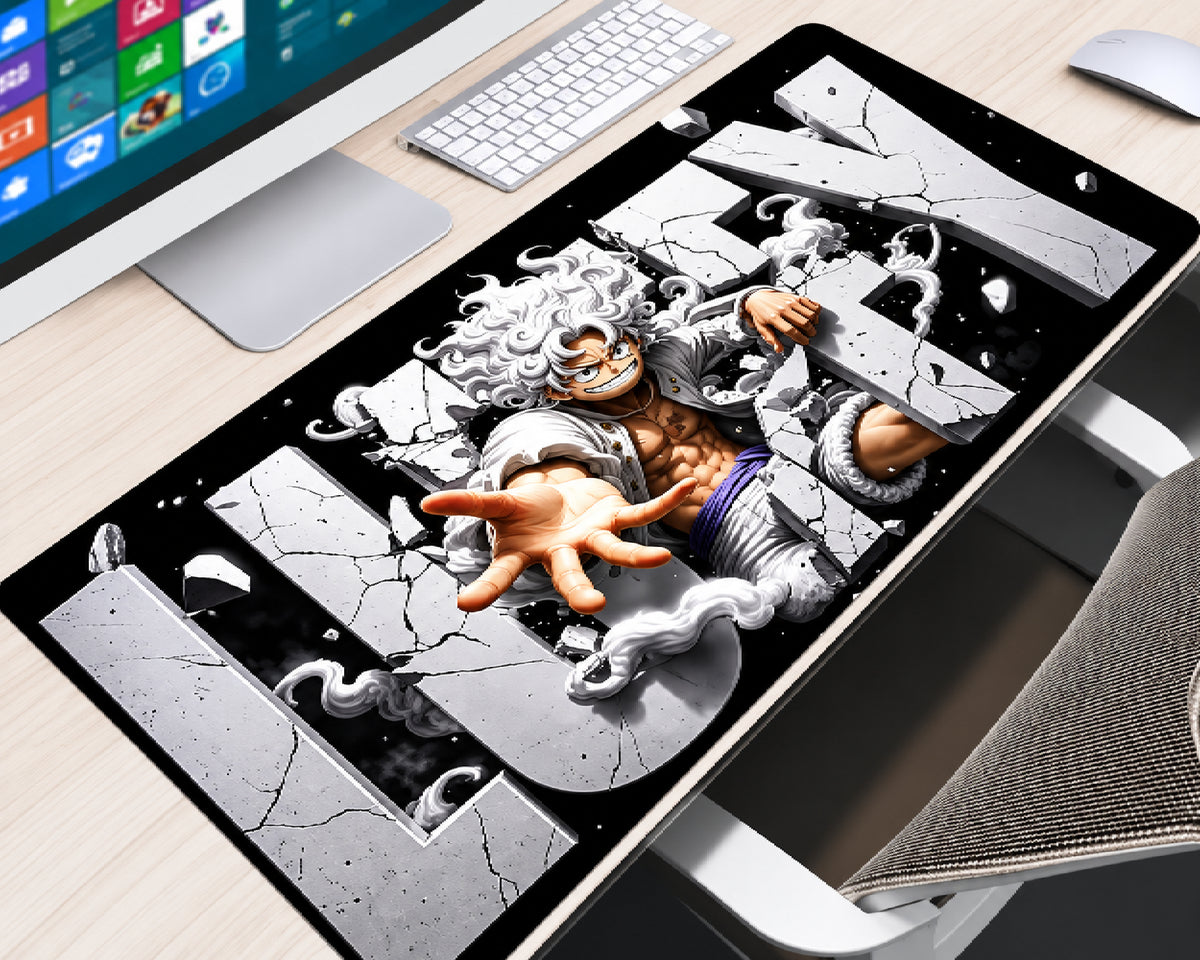 Extended One Piece gaming mouse pad featuring Monkey D. Luffy in Gear 5 form with flowing white hair, an outstretched hand, swirling white clouds, and cracked gray lettering against a black background, displayed on a light wood computer desk with a white keyboard, monitor, and white mouse.