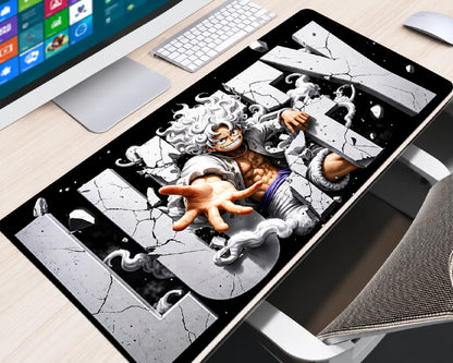 Extended One Piece gaming mouse pad featuring Monkey D. Luffy in Gear 5 form with flowing white hair, an outstretched hand, swirling white clouds, and cracked gray lettering against a black background, displayed on a light wood computer desk with a white keyboard, monitor, and white mouse.