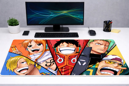 Large 24x12 inch One Piece mousepad featuring the faces of Luffy, Zoro, Nami, Sanji, and Usopp on a clean gaming desk setup.