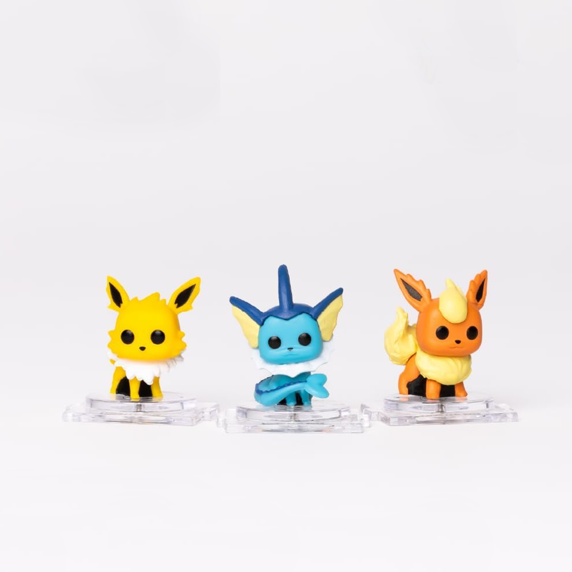Three small figurines on clear stands against a white background